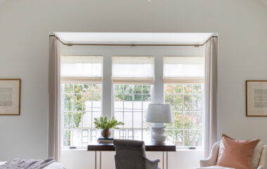 Charming cottage-style home bedroom with drapes and shades.