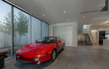 A modern museum home with a red sports car.