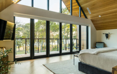 A luxury lakefront retreat bedroom with panoramic window views.