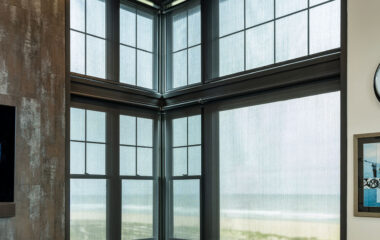 Beach and sea view through a window with automated shades.